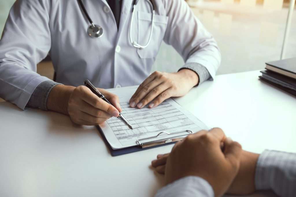 Doctor hand holding pen and talking to the patient about medication and treatment.
