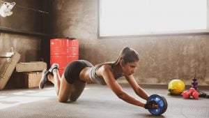 woman doing exercise by abs roller