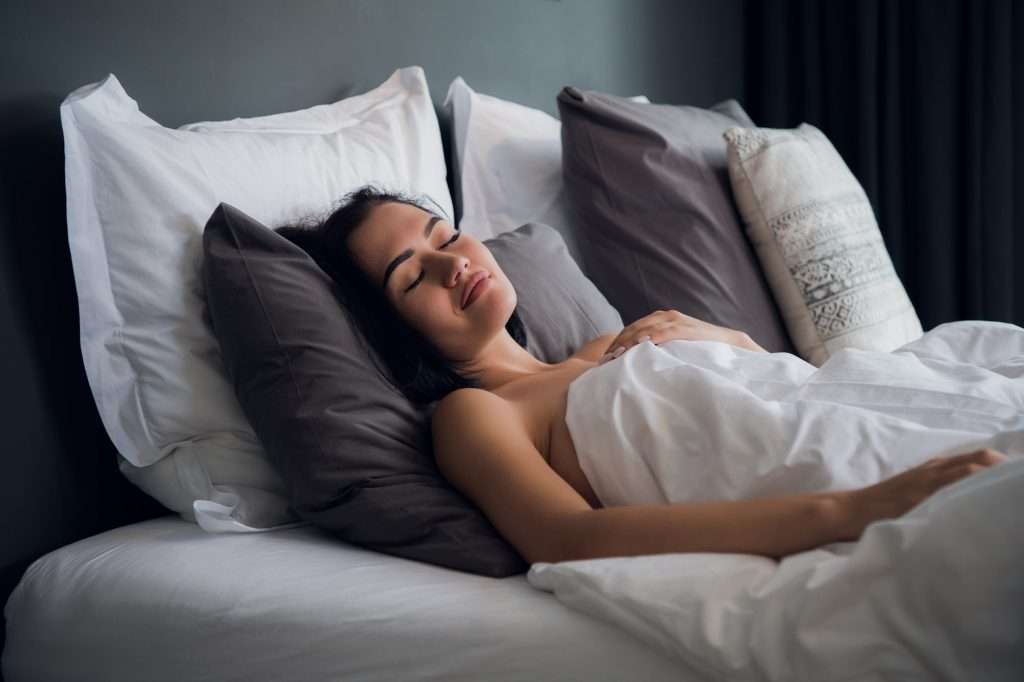 hotel, travel and happiness concept - beautiful woman sleeping in bed