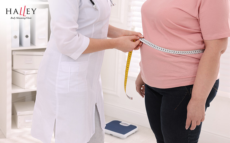 Doctor measuring a woman's waist in a clinic.