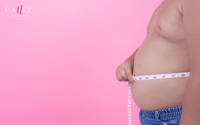 Person measuring waistline to track male body fat reduction.
