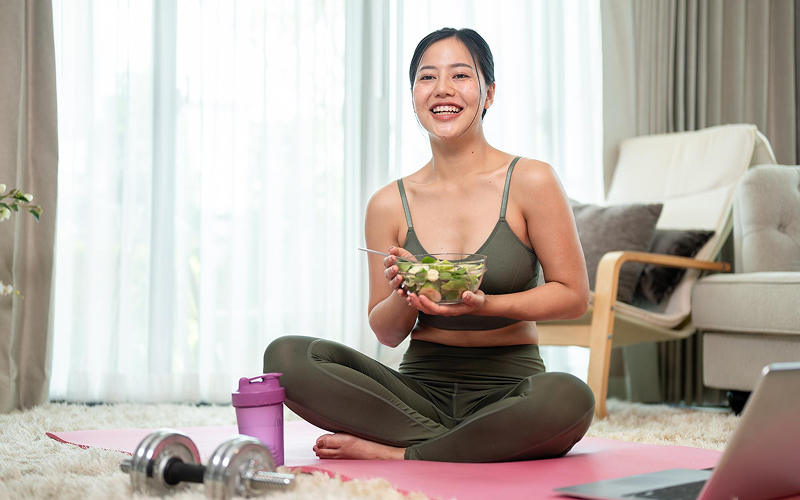 Woman in activewear eating healthy salad after a workout.