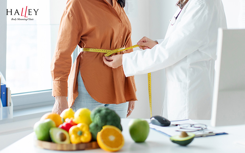 Halley Body Slimming Clinic | How to Lose Thigh Fat: From Lifestyle Changes to Non-Surgical Fat Reduction A doctor measuring a client's waistline.