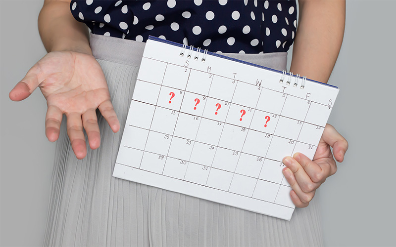 Woman holding calendar with question marks indicating irregular menopause periods